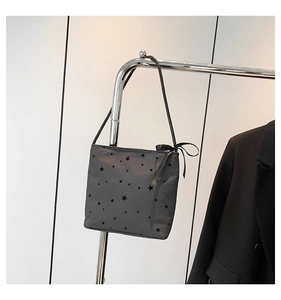 Detail of grey shoulder bag with black star prints and delicate ribbon bow on strap