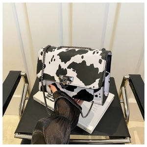 Close-up of stylish cow print small square bag with dark metal chain and secure lock buckle