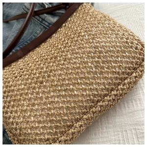 Close-up of hand-woven straw bag texture with brown leather edges and strap details