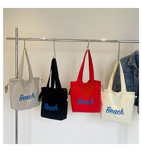 Close-up of four canvas tote bags with blue Beach prints and adjustable drawstring sides