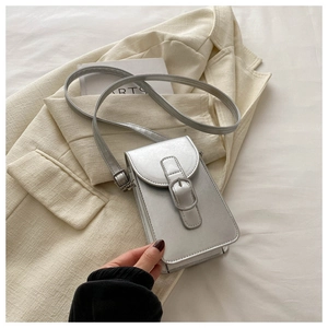 Detail of silver metallic phone bag with buckle on beige blazer and art props