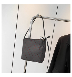 Detail of grey canvas tote bag with red heart pattern and black satin bow on zipper