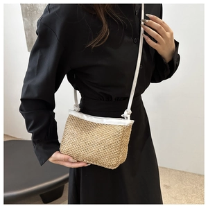 Detail of woven straw texture and white leather trim on a stylish summer crossbody bag