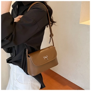 Close-up of brown PU leather shoulder bag featuring a silver bow and knotted strap detail