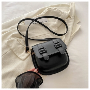 Detail of a matte black saddle crossbody bag featuring leather straps and gold metal hardware