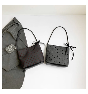 Detail of grey canvas heart print tote bag with black leather patchwork and ribbon