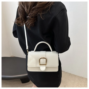 Sac bandoulière blanc en similicuir avec boucle dorée porté par un mannequin pour taille