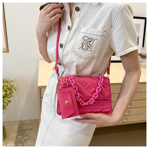 Detail view of pink quilted crossbody bag with chunky chain strap and mini pouch charm