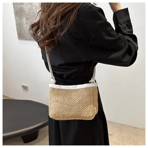 Detail of hand-woven straw crossbody bag with white leather trim and slim shoulder strap