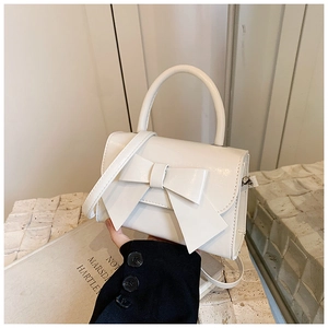 Détail du sac à bandoulière blanc orné d'un grand nœud et d'une poignée ronde chic