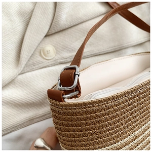 Détail du sac bandoulière en paille tressée avec bandoulière cuir et boucle argentée