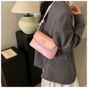 Detail of light pink shoulder bag with a silver metal bow buckle and smooth leather texture