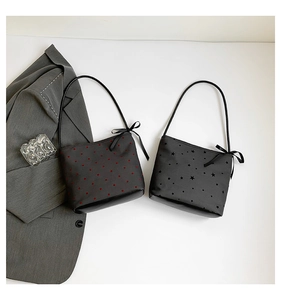 Close-up of black tote bags with heart and star patterns and ribbon bow strap details