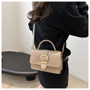 Détail d'un sac à bandoulière beige avec boucle fer à cheval dorée et similicuir lisse