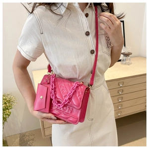 Detail of pink quilted crossbody bag with chunky chain and matching mini pouch accessory