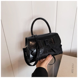 Détail du sac en cuir verni noir plissé avec un grand nœud élégant et une poignée ronde