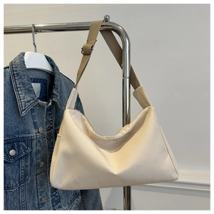 Detail of cream canvas bucket bag with adjustable khaki strap and minimal trapezoid design