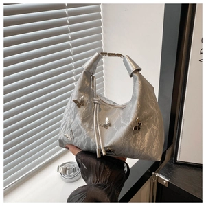 Gros plan d'un sac argenté métallisé avec breloques papillons et texture froissée