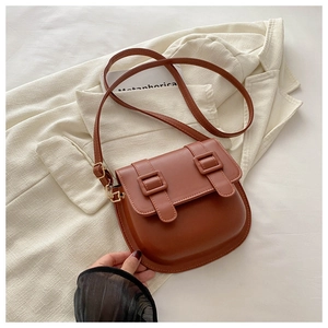 Detail of vintage brown saddle bag with double buckle straps on beige blazer