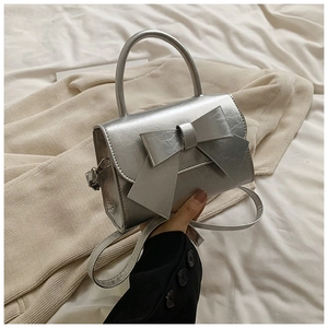 Détail du sac à main argenté métallisé avec gros nœud et poignée supérieure lisse