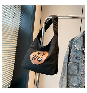 Detail of black canvas tote bag with a brown leather patch and embossed XY WG lettering