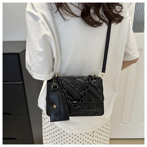 Detail of black quilted crossbody bag with FASHION lettering and removable mini pouch
