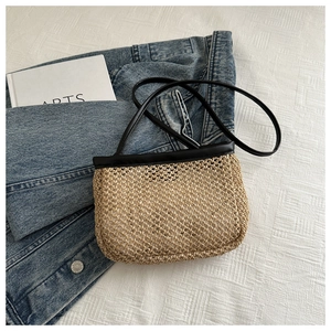 Detailed texture of woven straw material with black leather strap on a small bag