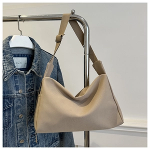 Close-up of beige canvas bucket bag with adjustable shoulder strap and silver buckle