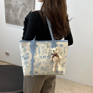 Fashion tote bag with blue graffiti prints, beige shoulder strap and teddy bear pendant