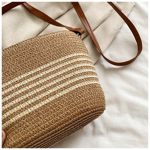 Détail du sac de plage en paille tressée avec bandoulière en cuir et texture rayée