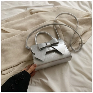 Détail du nœud métallique argenté sur un élégant sac carré bandoulière chic