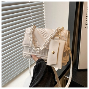 Detail of white quilted crossbody bag featuring a chunky chain and mini coin purse