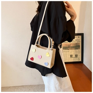 Détail du mini sac cabas crème avec écussons cœurs colorés et bandoulière amovible réglable