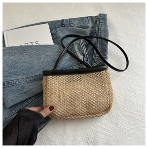 Detail of hand-woven straw crossbody bag with black leather trim and shoulder strap