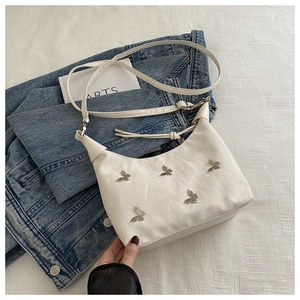 Détail d'un sac lune blanc avec papillons argentés sur cuir synthétique texturé