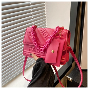 Detail of rose red quilted crossbody bag featuring fashion embossing and chunky chain handle