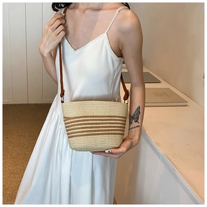 Détail du sac bandoulière en paille tressée avec rayures brunes et bandoulière cuir