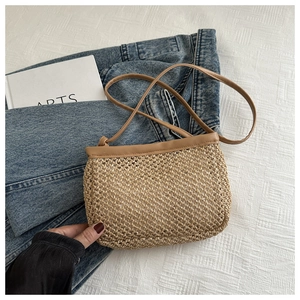 Detail of straw woven crossbody bag with brown faux leather straps on a casual setting