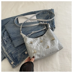 Sac argenté brillant avec détails papillons sur veste en jean et tissu blanc texturé