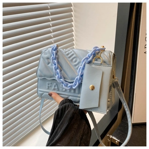 Detail of light blue quilted crossbody bag featuring embossed FASHION lettering and chain