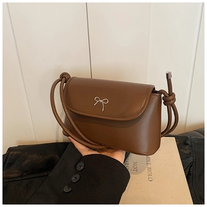 Detail of a brown PU leather shoulder bag featuring a silver metal bow buckle