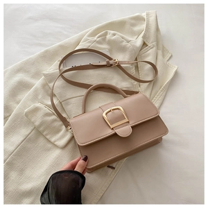 Sac bandoulière beige minimaliste sur veste avec boucle carrée dorée élégante