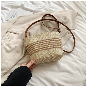 Détail d'un sac bandoulière en paille tressée avec rayures brunes et sangle