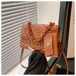 Detail of caramel quilted crossbody bag with FASHION embossed letters and chain handle