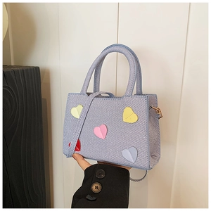 Détail du petit sac bleu ciel texturé avec patchs en cuir en forme de cœur et poignée