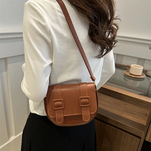 Minimalist caramel brown leather saddle bag with vintage buckle straps for women's crossbody wear