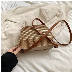 Gros plan sur la texture en paille tressée et coutures en cuir du sac de plage