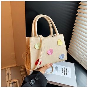 Gros plan d'un sac cabas beige texturé avec des patchs colorés en forme de cœur