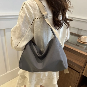 Large dark grey nylon crossbody bag with adjustable wide beige strap for daily commute