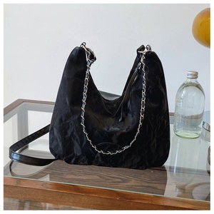 Dettaglio della borsa tote nera stropicciata con catena argento e finitura lucida
